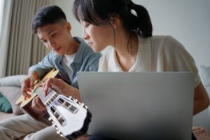 two people learning how to play guitar from online lessons