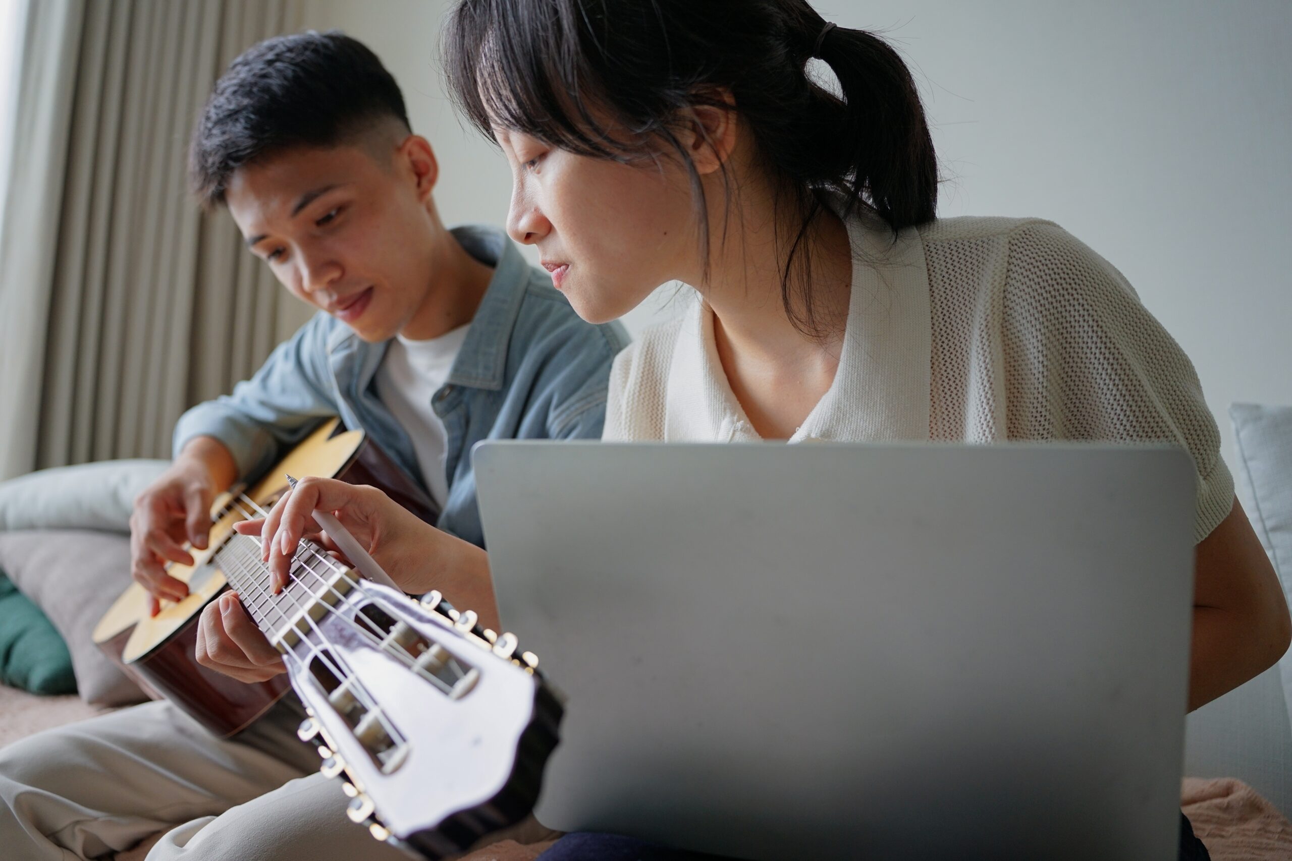 two people learning how to play guitar from online lessons