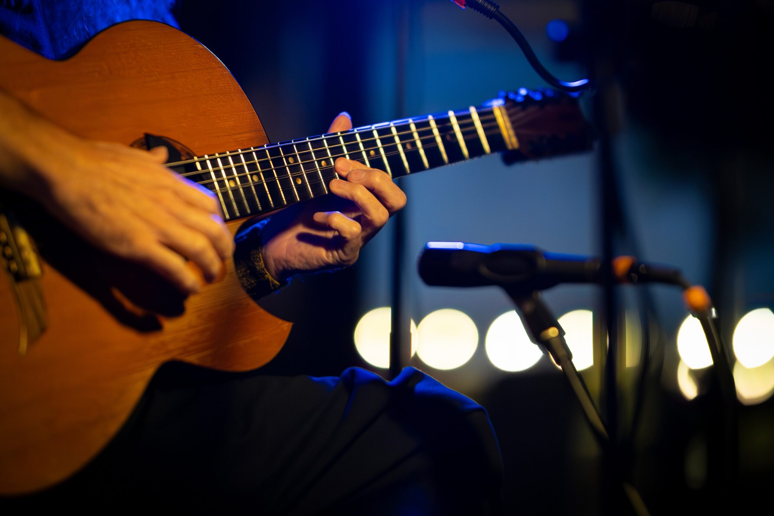 Musician playing acoustic guitar on stage during live performance
